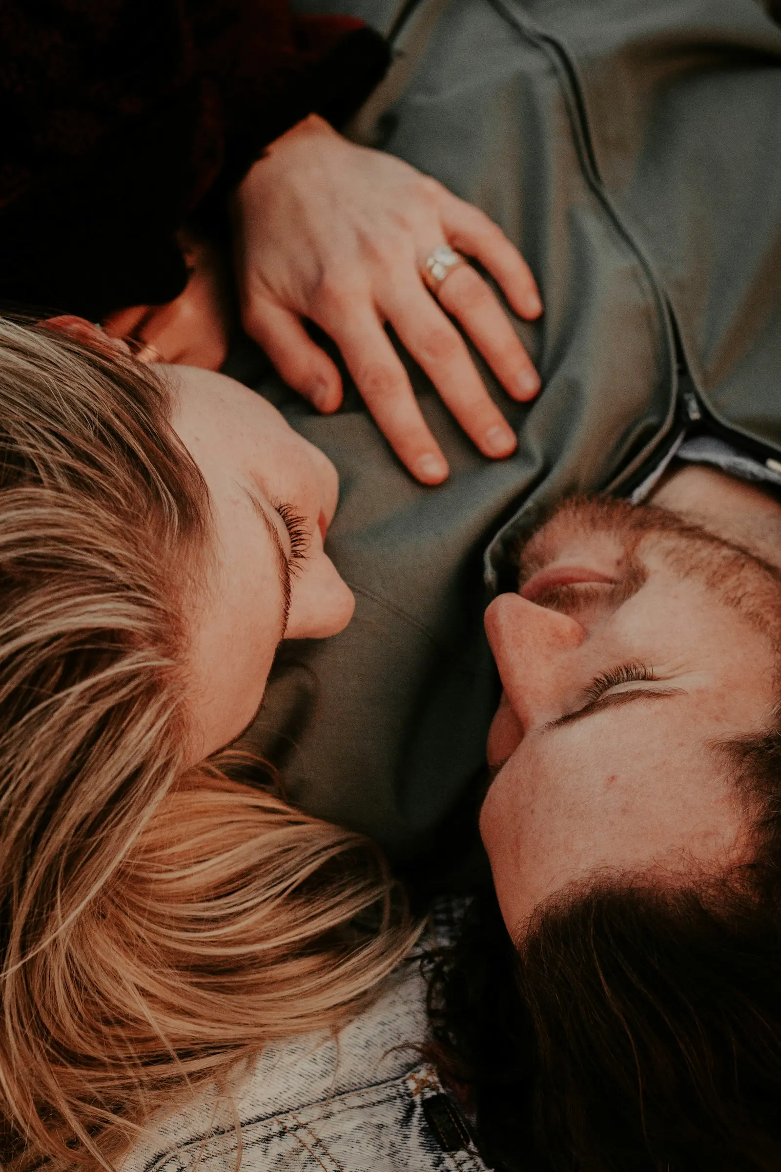 A man and woman relax together on a blanket, enjoying a peaceful moment outdoors under a clear blue sky.
